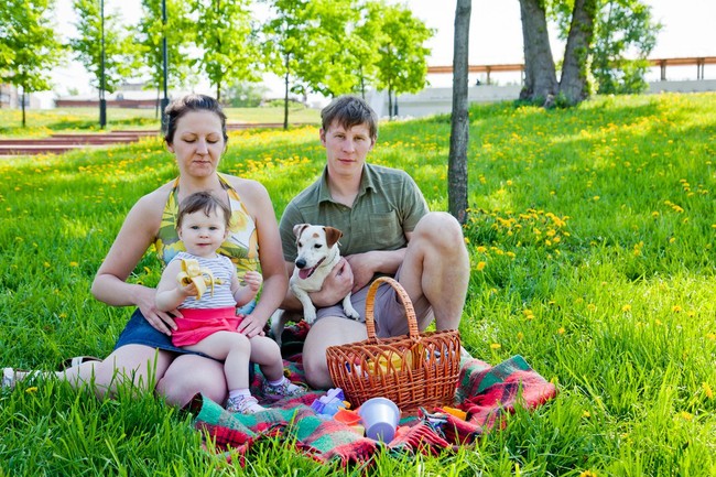 Rodzice, dziecko i pies piknik w parku.