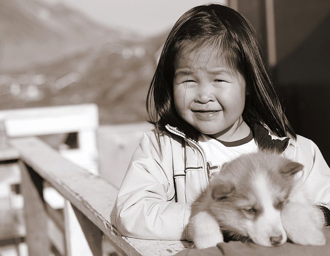 Iniuci i psy - dziewczynka trzymajaca szczeniaka Dziewczynka Inuit trzymająca szczeniaka